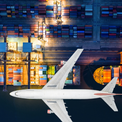 Aeroplane flying over cargo ships at a dock